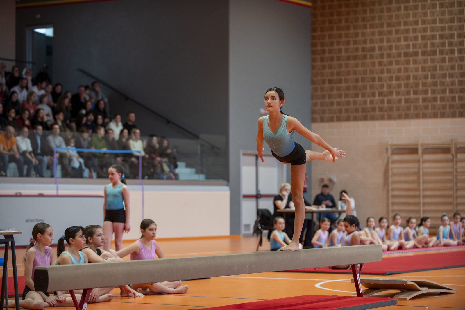 Atleta in esercizio sulla trave durante la gara di ginnastica artistica