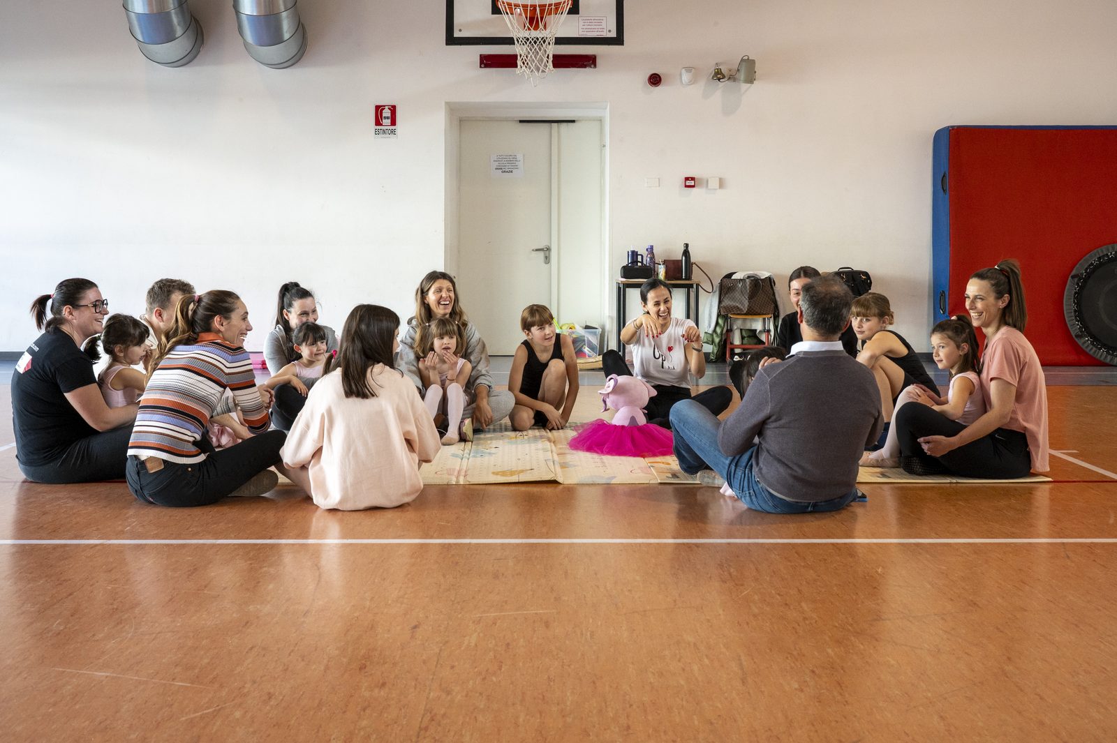 Allieve e famiglie sedute in cerchio in palestra durante un momento condiviso