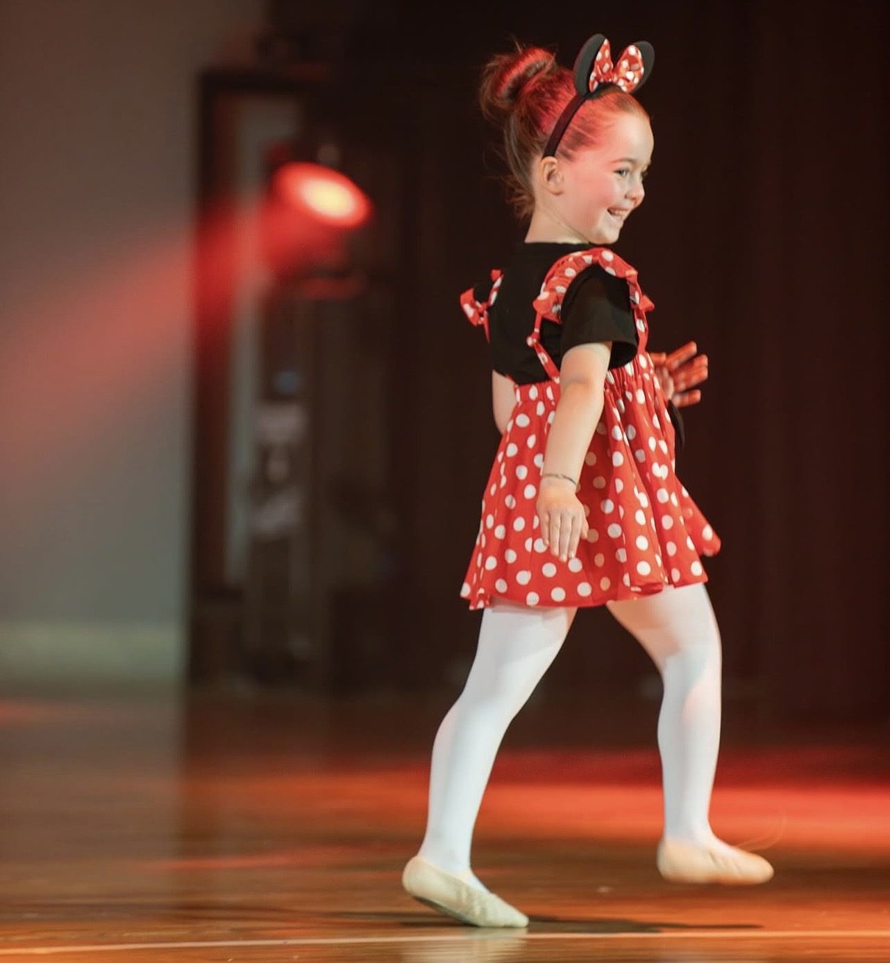 Bambina in costume sorride sul palco durante il saggio di fine anno